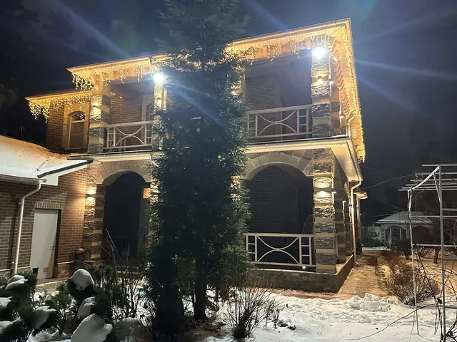 Бахрома тёплого свечения на двухэтажной вилле с балконами